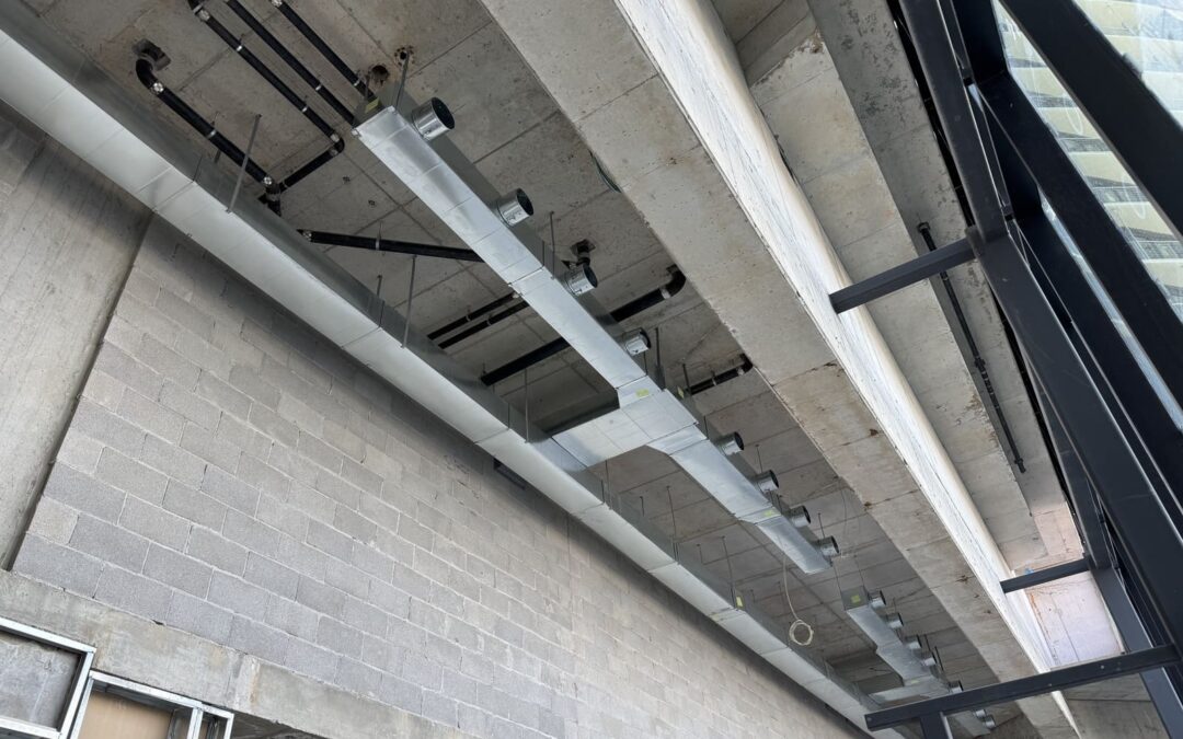 Ceiling-mounted HVAC ventilation system in a high-rise building, showing metal ductwork, vents, and mechanical components used for air circulation during summer conditions.